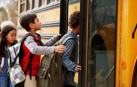 a line of children filing into a school bus unaware of their peers bed bug infestation